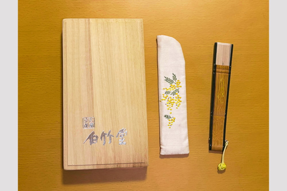 京都で購入した扇子を箱から出した様子。木箱とミモザ柄の扇子、専用ケースが並ぶ